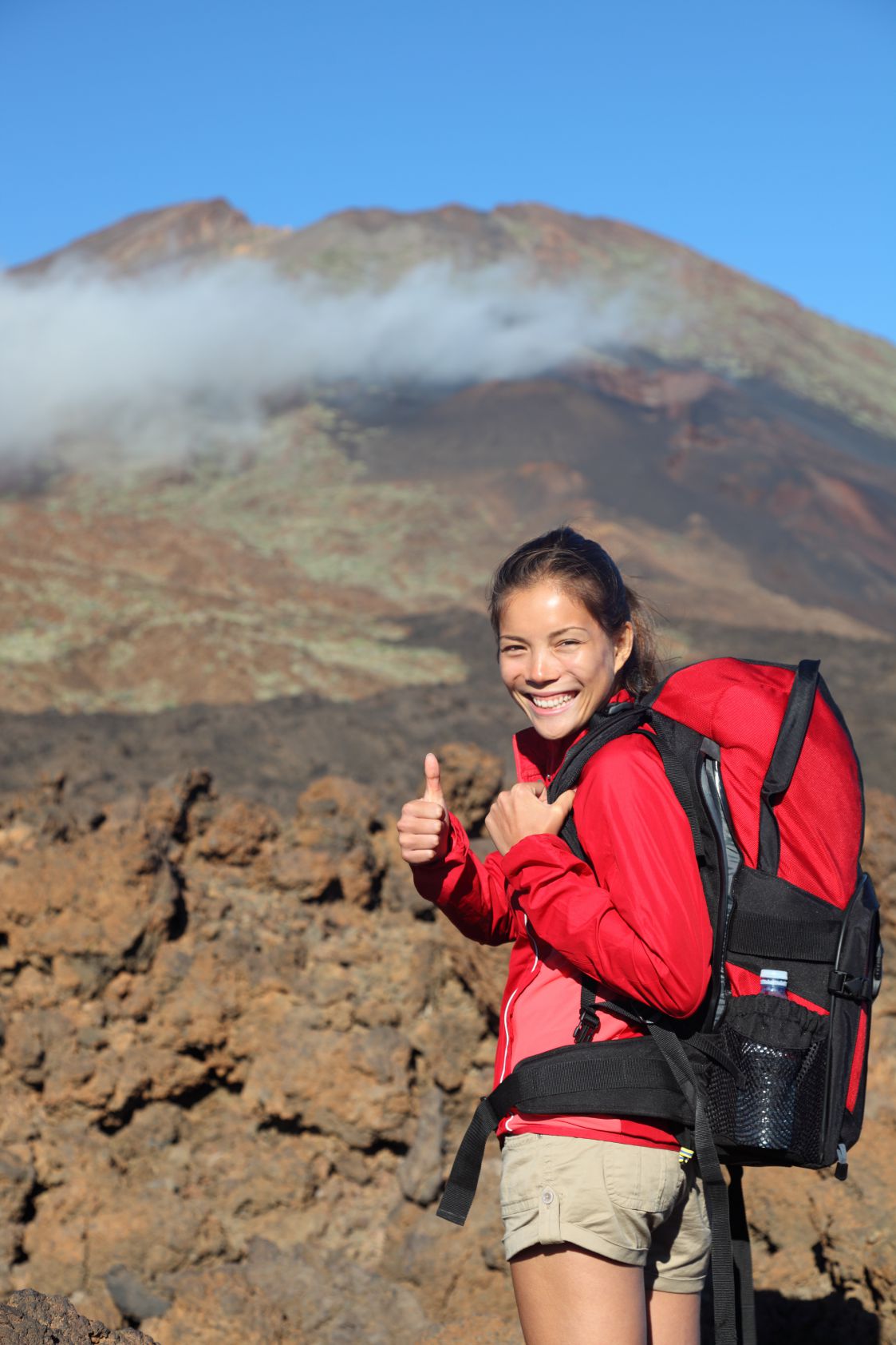 Healthy lifestyle concept- happy woman hiker giving thumbs up before summit hike. Beautiful young Asian / Caucasian model. Shows Pico Viejo, Teide National Park, Tenerife with lots of copyspace.